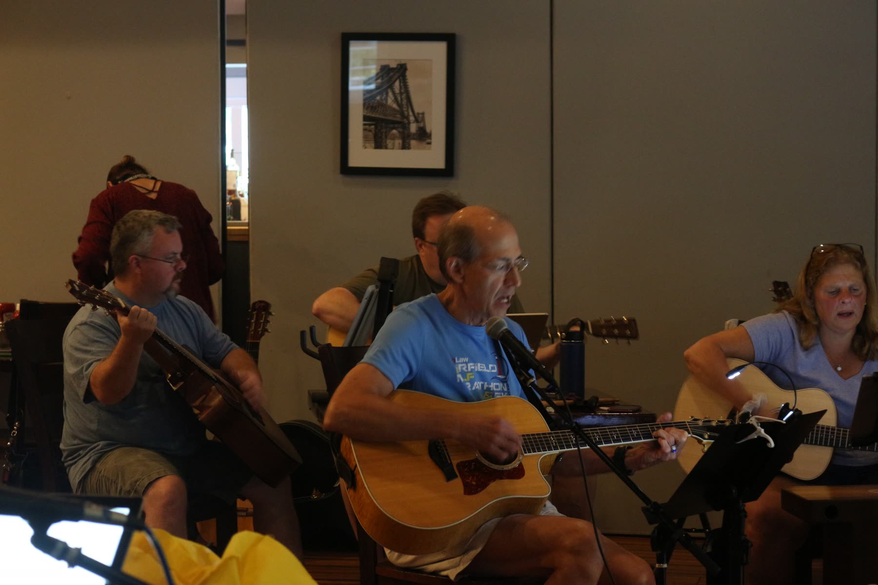 Guitarists playing and singing together at an indoor jam session.