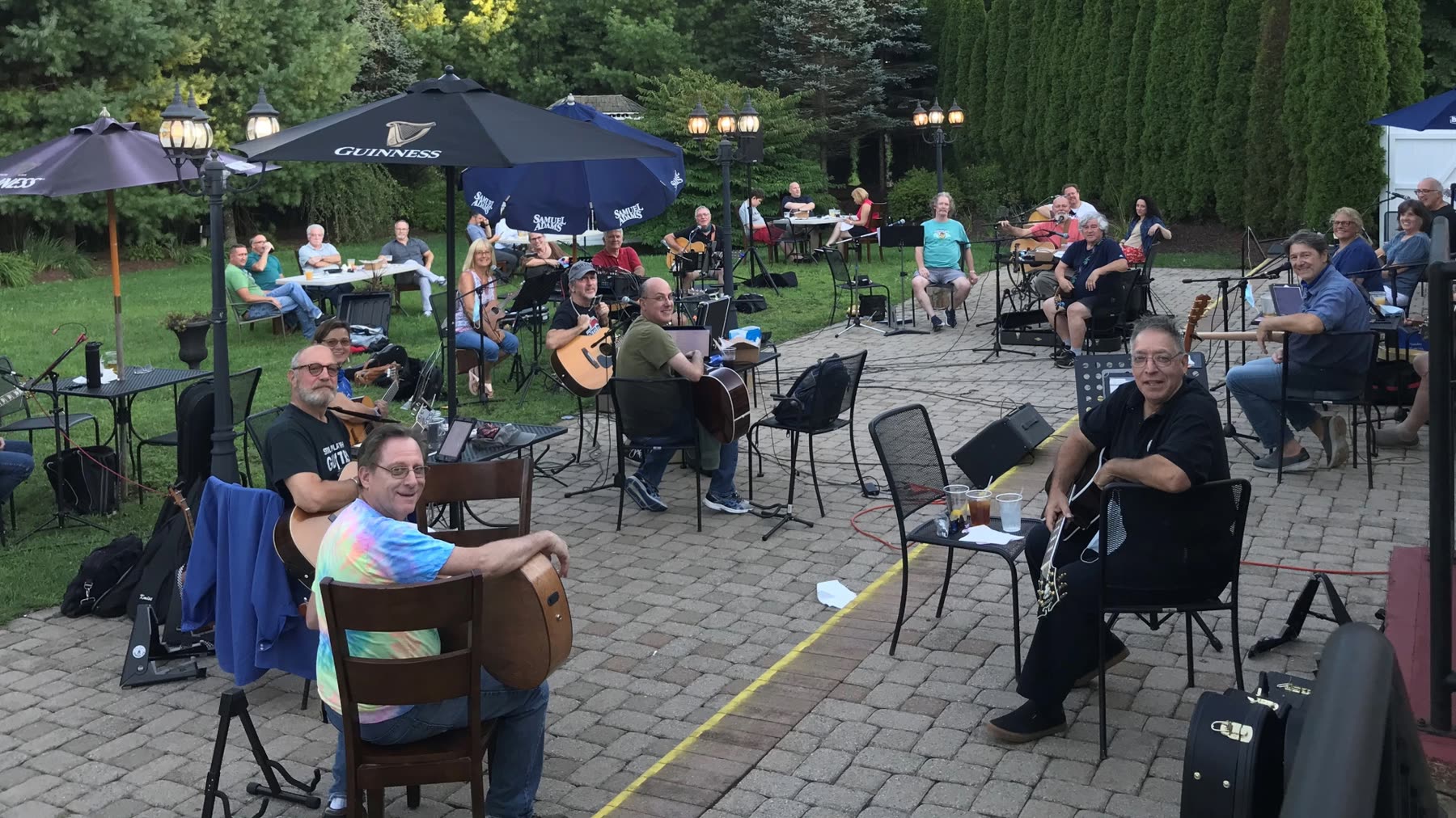 A large group of musicians with guitars playing together on an outdoor patio.